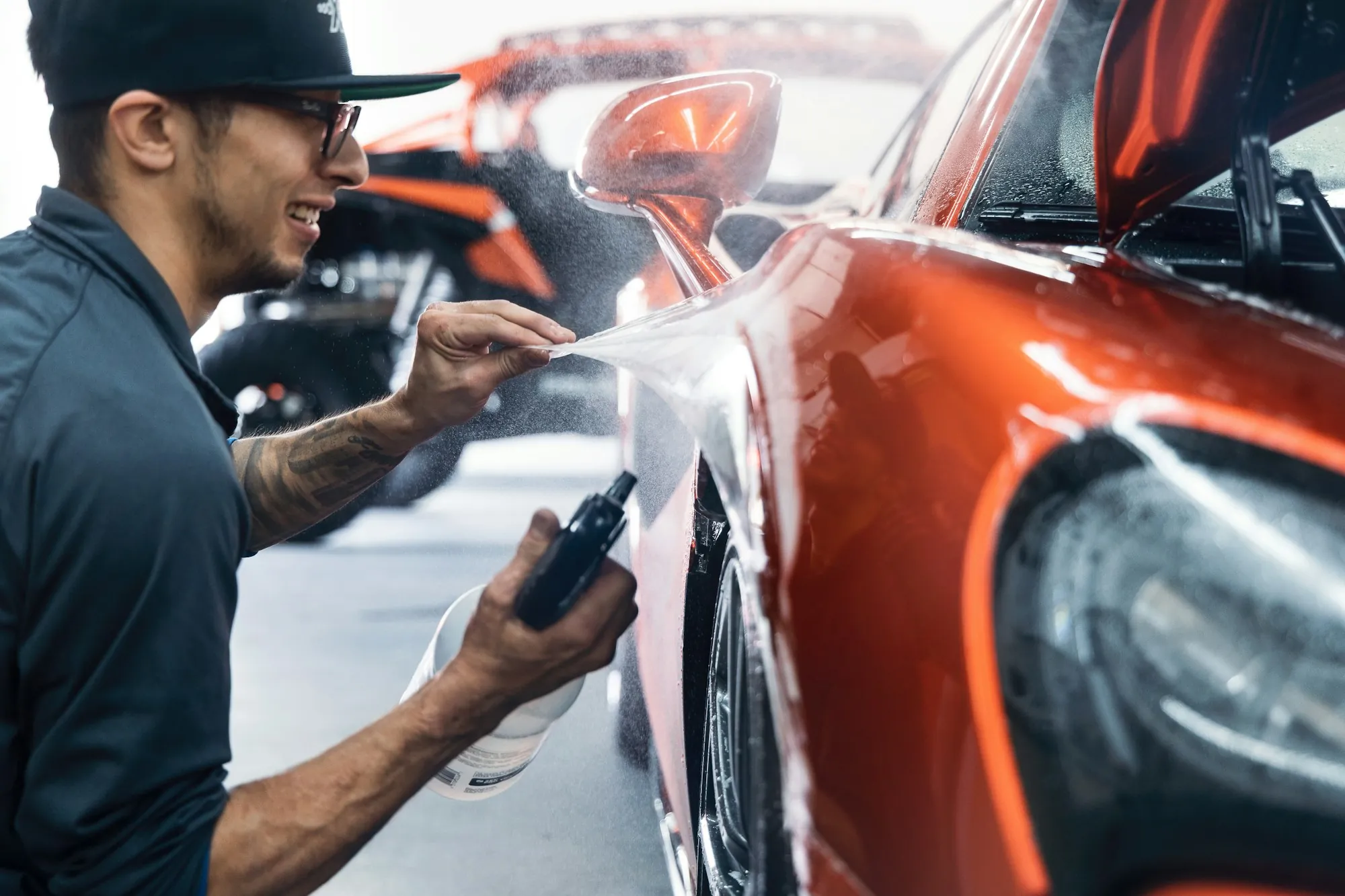 Technician spraying and wiping the paint of an orange car